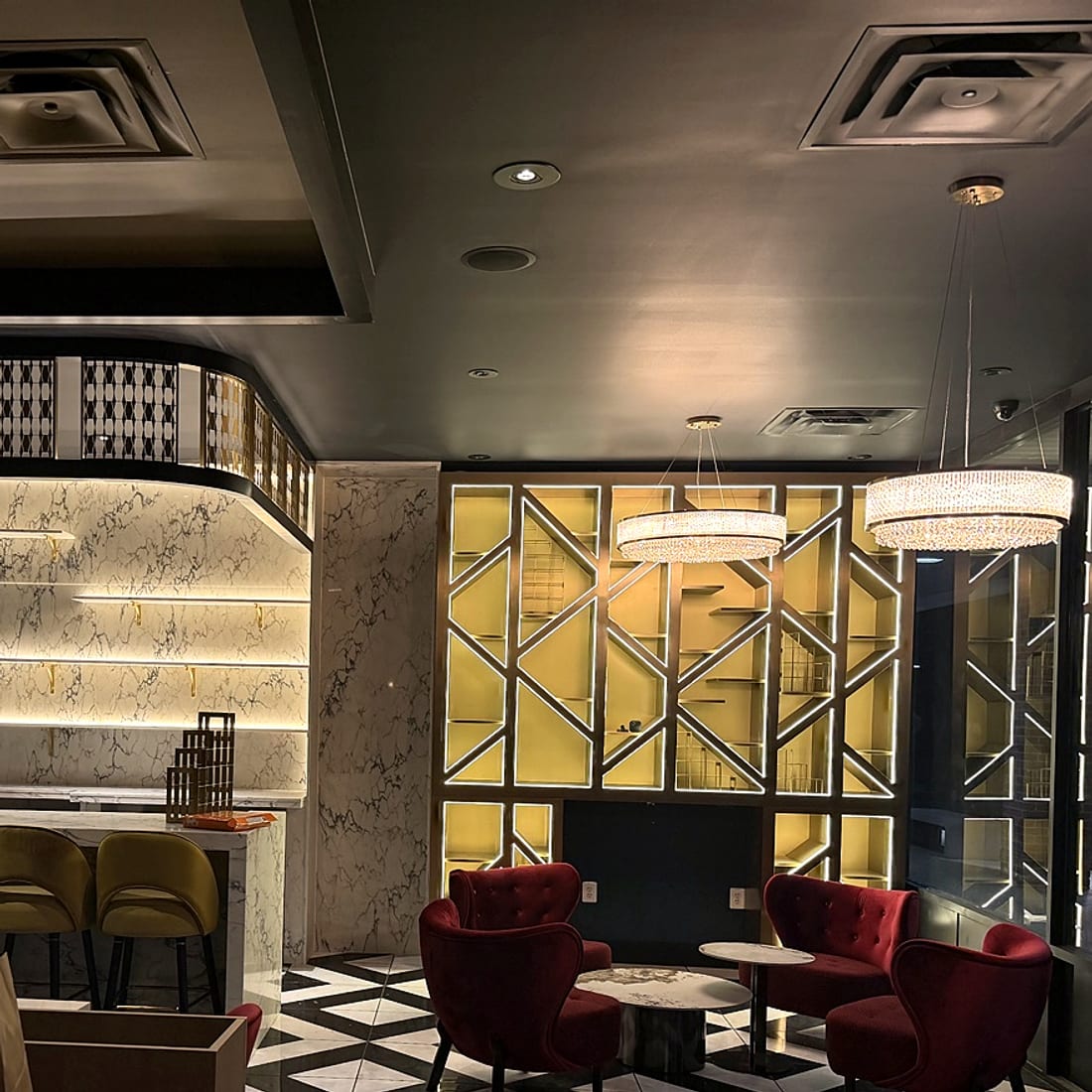 Backlit marble bar with olive velvet stools and crystal chandelier lounge